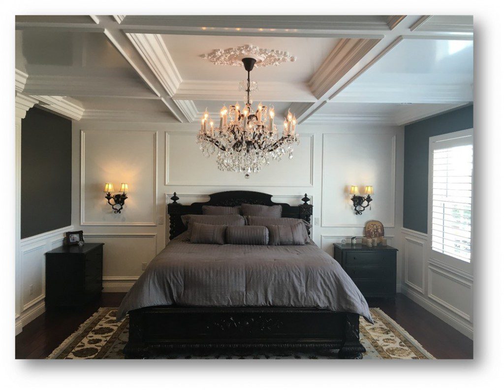 A bedroom with a bed, two nightstands and a chandelier.