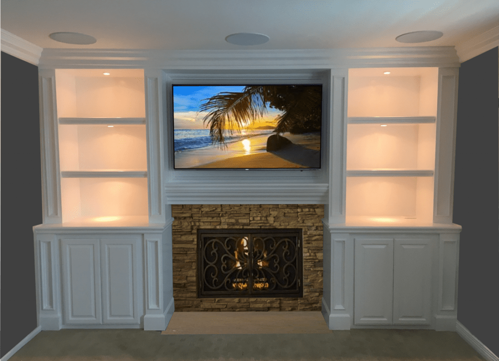 A fireplace with built in shelves and a television mounted on it.