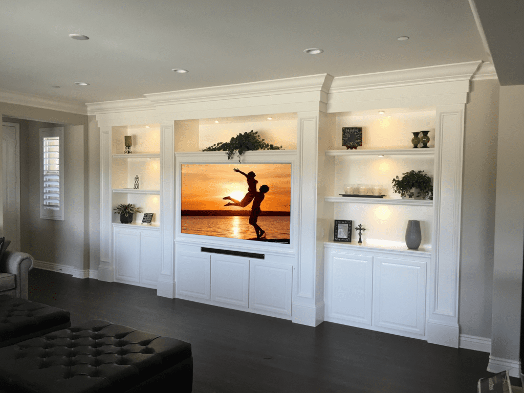 A living room with white built in cabinets and shelves.