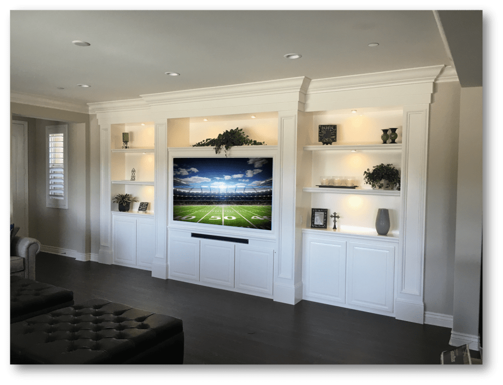 A living room with white built in cabinets and a flat screen tv.