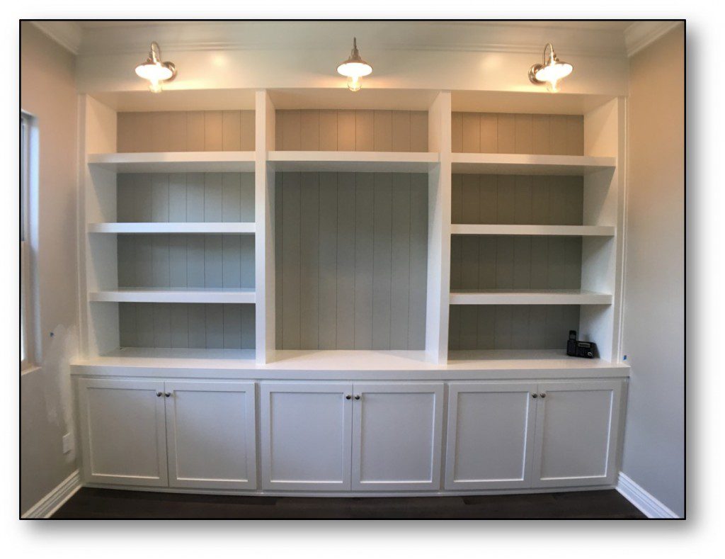 A white built in bookcase with lights on top.