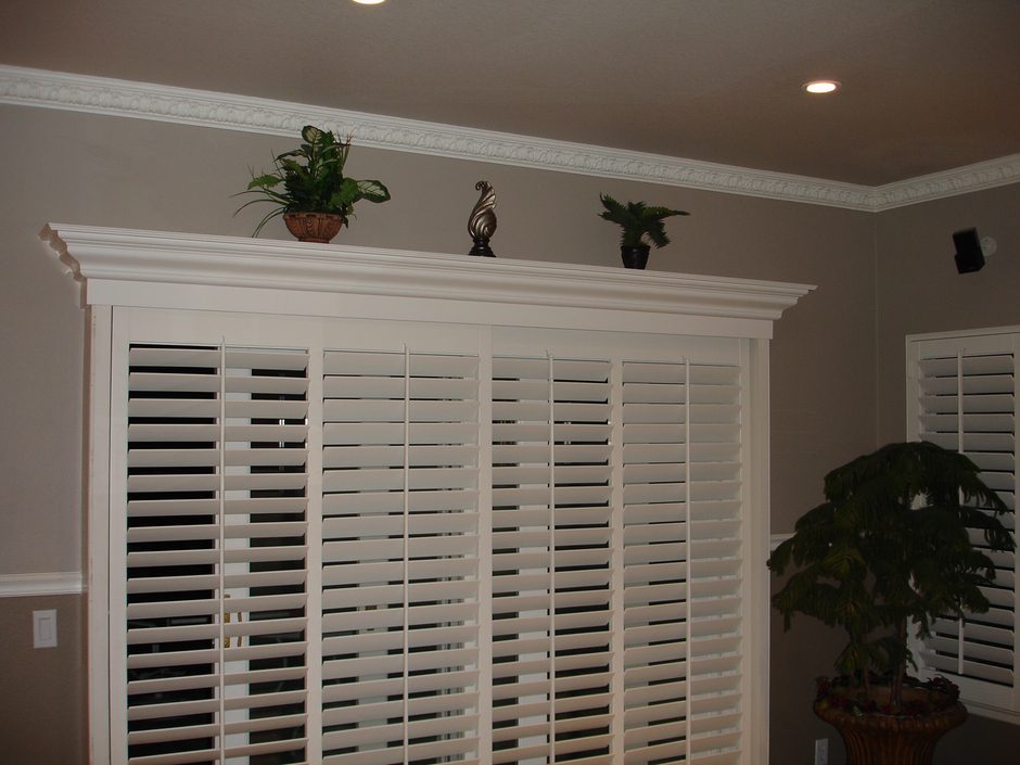 A room with a large window and plants on the top of it.