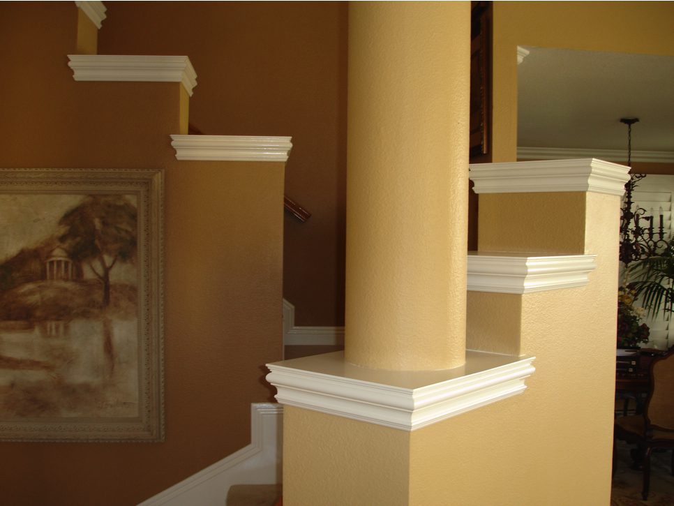 A staircase with pillars and painting in the background.