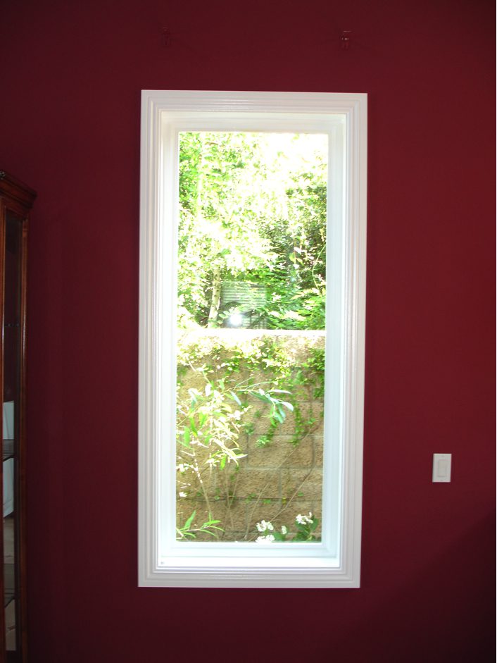 A window in the corner of a room with red walls.