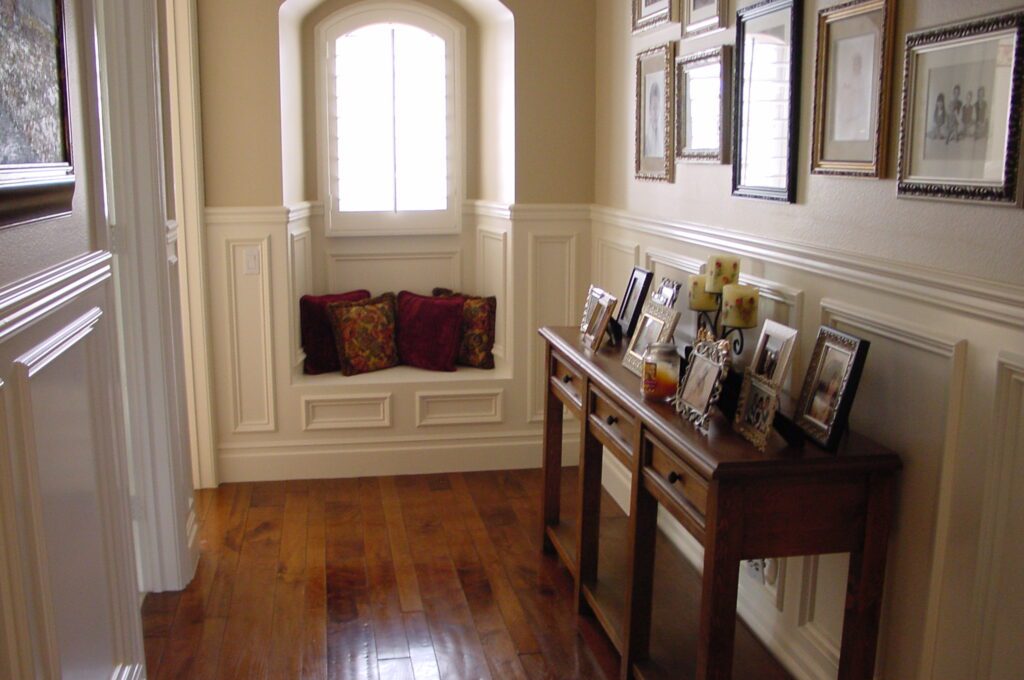 A hallway with a window seat and pictures on the wall.