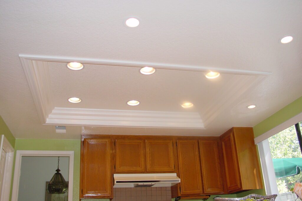 A kitchen with lights on the ceiling and cabinets