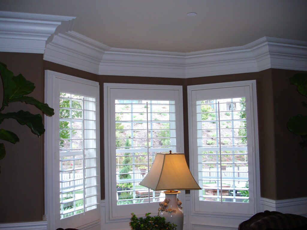 A lamp sitting in front of three windows.