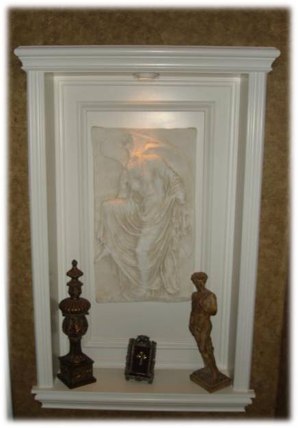 A white wall with statues and a picture.