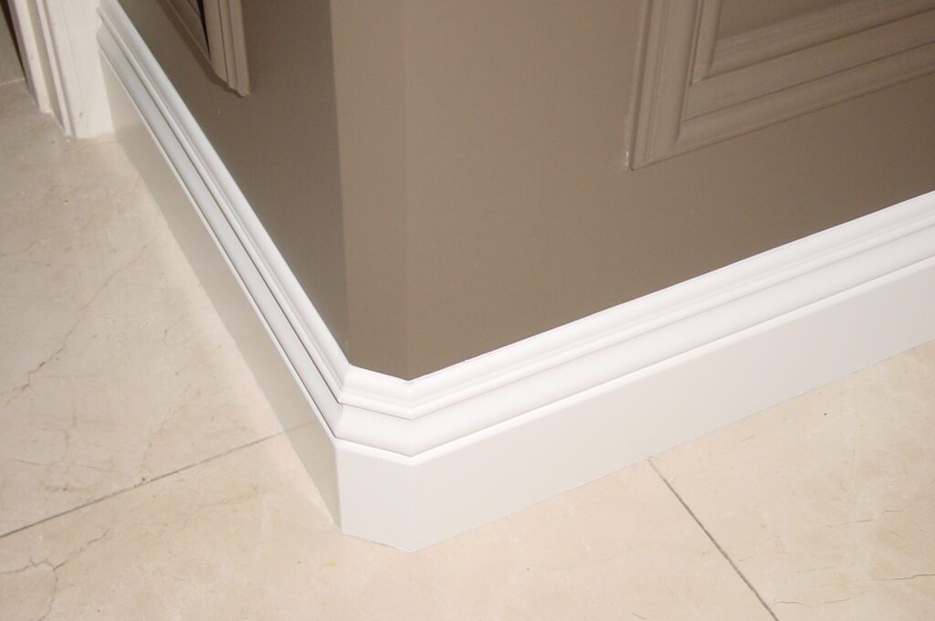 A corner of a room with white trim and beige walls.