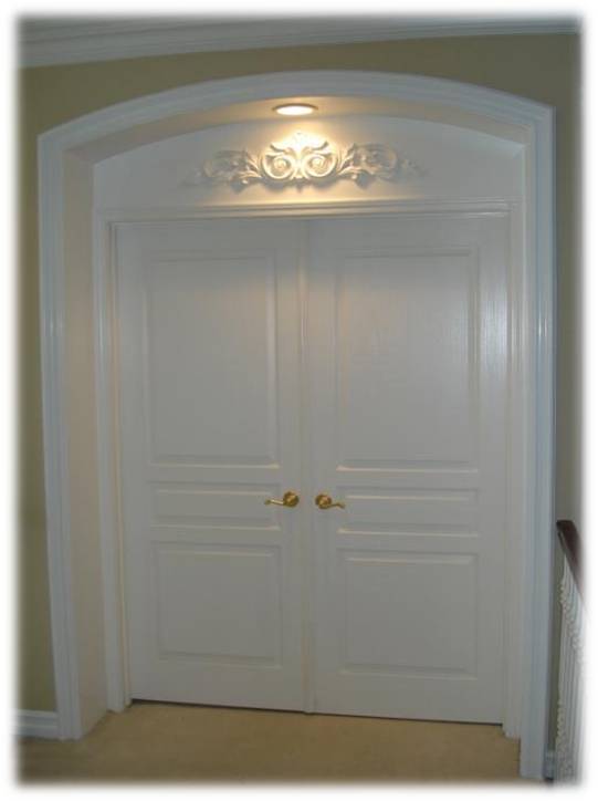 A white door with two brass knobs and a light above it.