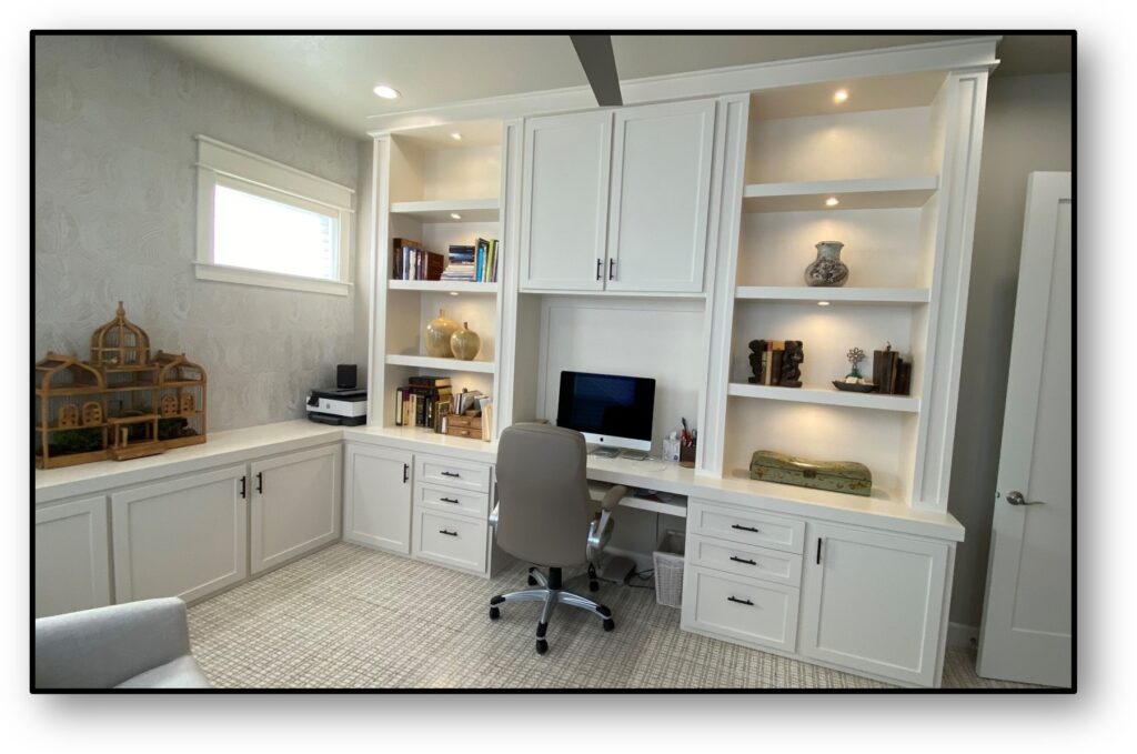 A home office with white cabinets and desk.