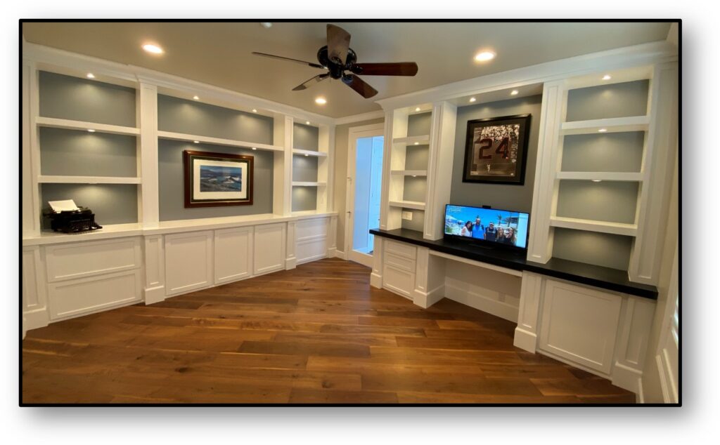 A room with white cabinets and wood floors.